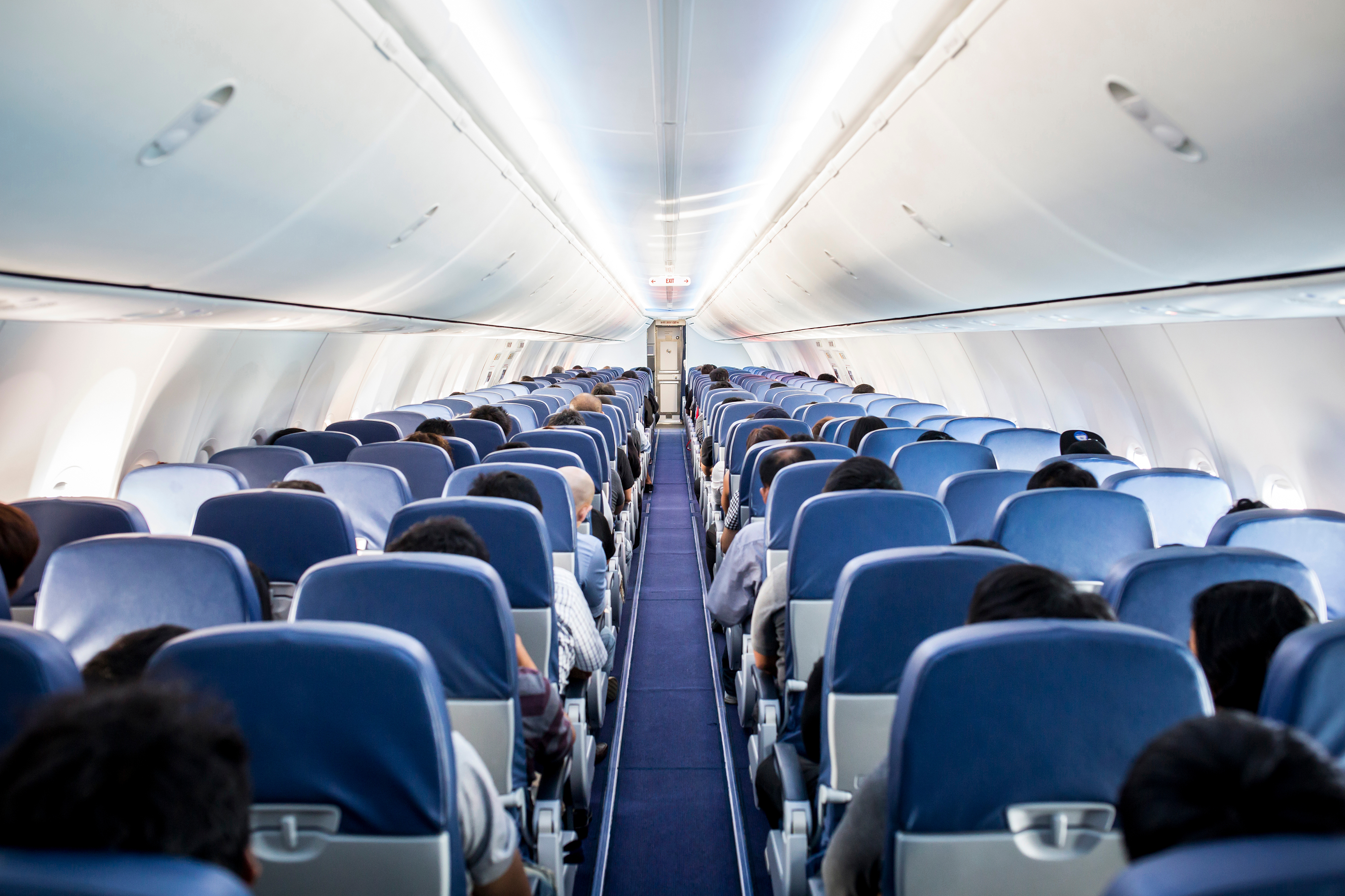 six rows of people seated on a plane with an aisle down the middle